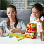 Two girls building with colorful blocks at a table.